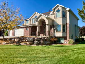 View of front of house featuring brick siding, a front yard, and stucco siding