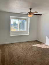 Unfurnished room featuring carpet, a textured ceiling, and ceiling fan.  Window seat with storge