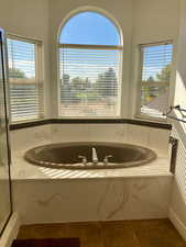 Bathroom featuring a relaxing tiled tub, tile patterned floors, and plenty of natural light