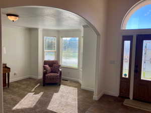 Carpeted entrance foyer featuring crown molding and a textured ceiling