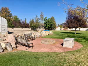 View of yard featuring an outdoor fire pit, a shed, and a patio area