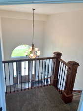 Stairway with a chandelier and carpet