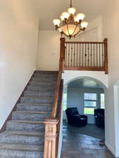 Stairs with a notable chandelier and carpet