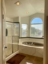 Bathroom featuring shower with separate bathtub, vaulted ceiling, a textured ceiling, and tile patterned flooring