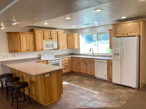 Kitchen featuring white appliances (included), a textured ceiling, sink, and kitchen peninsula, Hickory Cabinets