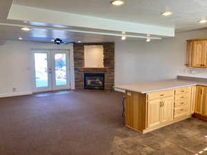 Kitchen featuring kitchen peninsula, ceiling fan, a textured ceiling, a fireplace, and dark colored carpet