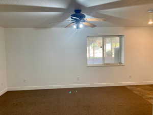 Unfurnished room with dark colored carpet, a textured ceiling, and ceiling fan