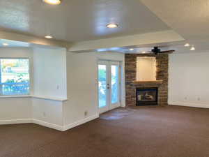 Unfurnished living room with french doors, carpet floors, a textured ceiling, and a fireplace