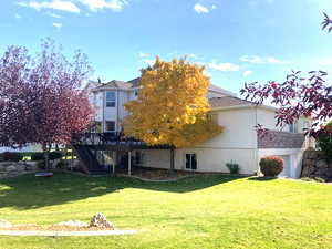 Back of house with a deck and a lawn