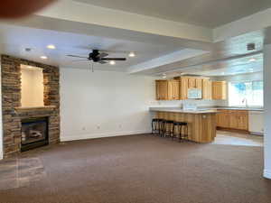 Kitchen with white appliances, light brown cabinetry, a textured ceiling, kitchen peninsula, and a breakfast bar area