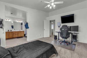 Carpeted bedroom with ensuite bathroom and ceiling fan