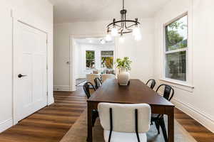 Dining room with dark hardwood / wood-style floors and a chandelier