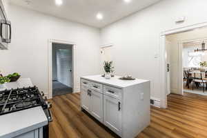 Kitchen with white cabinetry, gas range oven, dark hardwood / wood-style floors, and a kitchen island