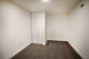 Bedroom with a closet and dark colored carpet