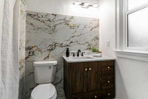 Bathroom with tile walls, vanity, and toilet