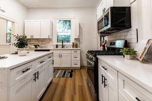 Kitchen with tasteful backsplash, appliances with stainless steel finishes, sink, dark hardwood / wood-style flooring, and white cabinets