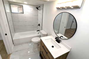 Full bathroom with vanity, tiled shower / bath combo, and toilet