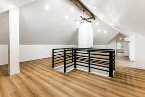 Bonus room featuring lofted ceiling with beams, light hardwood / wood-style floors, and ceiling fan