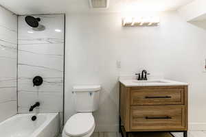 Full bathroom featuring vanity, tiled shower / bath combo, and toilet