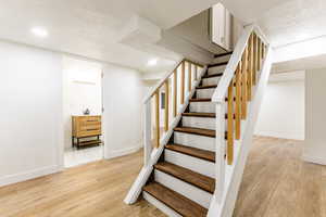 Staircase featuring hardwood / wood-style floors, a textured ceiling, and sink