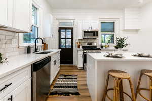 Kitchen with a healthy amount of sunlight, a breakfast bar area, wood-type flooring, sink, and stainless steel appliances