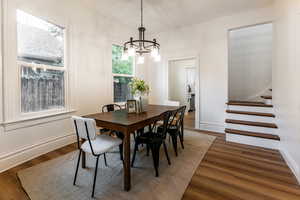 Dining space featuring an inviting chandelier, dark hardwood / wood-style floors, and a healthy amount of sunlight