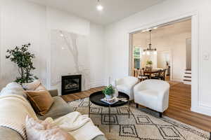 Living room with a notable chandelier, wood-type flooring, and a high end fireplace