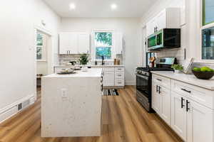 Kitchen with white cabinets, stainless steel appliances, light wood-type flooring, and plenty of natural light