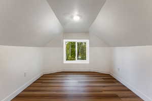 Additional living space with lofted ceiling and dark wood-type flooring