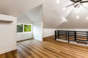 Additional living space featuring ceiling fan, a wall mounted AC, lofted ceiling, and hardwood / wood-style floors