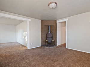 Unfurnished living room with carpet and a wood stove