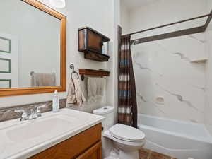 Full bathroom with tile patterned floors, vanity, toilet, and shower / bath combo with shower curtain