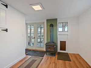 Doorway featuring french doors, a wood stove, light hardwood / wood-style flooring, and plenty of natural light