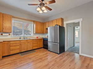 Kitchen with sink, stainless steel fridge, plenty of natural light, stove, and light wood-type flooring