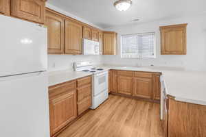 Kitchen featuring white appliances, sink, and light wood-type flooring