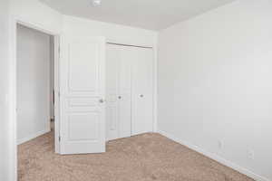 Unfurnished bedroom with light carpet and a closet