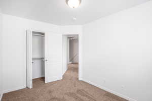 Unfurnished bedroom with light carpet and a closet