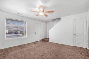 Carpeted spare room featuring ceiling fan