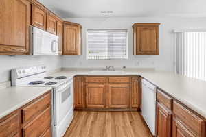 Kitchen with sink, light hardwood / wood-style floors, and white appliances