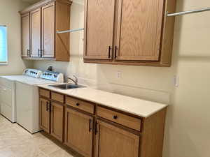 Spacious clothes washing area featuring cabinets, independent washer and dryer, sink, hanging areas and light tile patterned floors