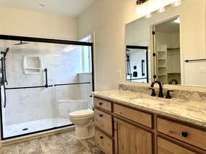 Primary luxurious bathroom with granite vanity, and  frameless glass shower enclosure with top-of-the line features on a stunning tile floor