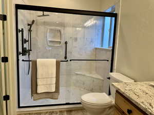 Primary Bathroom featuring updated vanity, toilet, and a updated shower with shower door