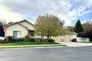 View of front facade featuring a front lawn, a two-car oversized garage and fenced yard with beautiful landscaping