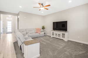 Living room with hardwood / wood-style floors and ceiling fan with notable chandelier