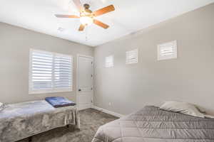 Bedroom featuring light carpet, multiple windows, and ceiling fan