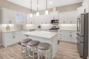 Kitchen featuring stainless steel appliances, sink, light wood-type flooring, and white cabinets