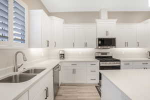 Kitchen featuring sink, white cabinetry, stainless steel appliances, light stone counters, and light hardwood / wood-style flooring