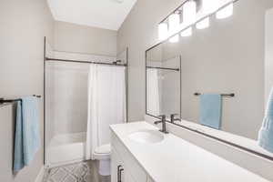 Full bathroom with vanity, shower / bath combo with shower curtain, and toilet