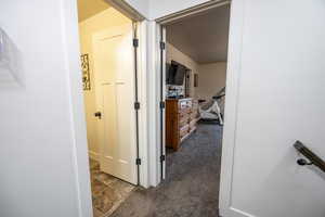 Hall with dark colored carpet and a textured ceiling