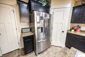 Kitchen featuring light stone countertops and stainless steel refrigerator with ice dispenser